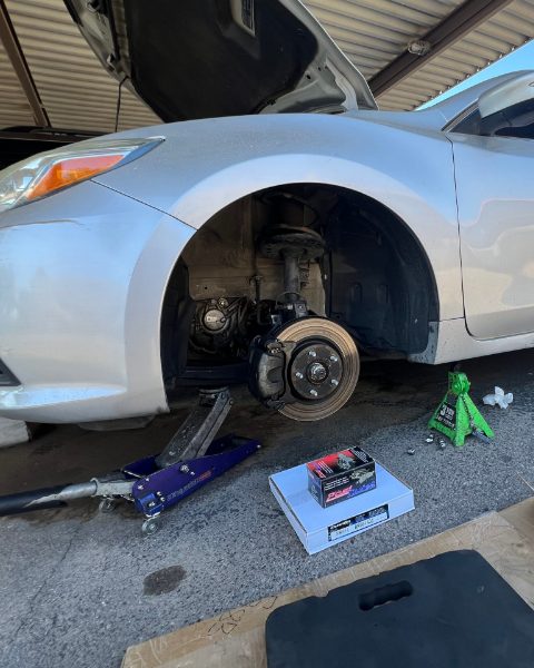 Nissan Altima on a jack with the front wheel off during a mobile brake job at the customer&rsquo;s home